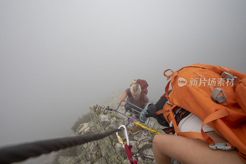 在雾中，一名年轻女子爬上via ferrata